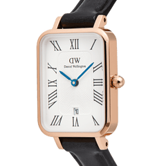 Close-up of the Quadro Roman Numerals Date Sheffield Rose Gold watch, showcasing its rectangular rose gold case, white guilloché dial with black Roman numerals, blue hands, and date window at six o’clock, paired with a black leather strap.