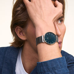 A person wearing the Classic Piano Link Arctic Silver watch with a brushed arctic blue dial and silver piano link strap, styled with a blue jacket and white top.