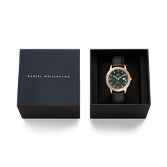 Daniel Wellington Iconic Sheffield Automatic Rose Gold watch with an emerald green dial and black leather strap, presented in an open signature gift box beside its matching lid.