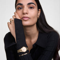 A woman wearing the Daniel Wellington Iconic Link gold watch and Classic Lumine gold bracelet with crystal accents, styled together on her wrist for a refined, modern look.