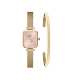 Rectangular gold watch with a blush pink dial and gold mesh strap, paired with a minimalist gold bracelet engraved with the Daniel Wellington signature.
