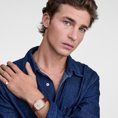 A person wearing the Daniel Wellington Marlon & Classic Mini Signet Ring Rose Gold Set, featuring a square-faced rose gold watch with a brown leather strap and a minimalist rose gold signet ring, styled with a denim shirt for a modern, elegant look.