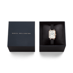Quadro Roman Numerals Date Sheffield Rose Gold watch with a rectangular rose gold case and black leather strap, elegantly presented in a signature Daniel Wellington gift box.