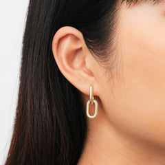 Crystal Link Earrings Gold featuring an elongated gold-plated link with sparkling cubic zirconia, worn on ear.