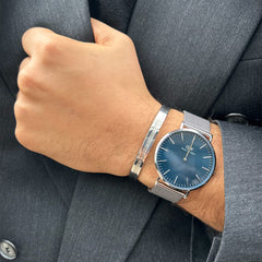 Classic Mesh Arctic Silver watch with a deep blue dial and silver mesh strap, styled on the wrist with a matching silver bracelet and a tailored suit.