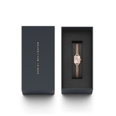 Quadro Mini Melrose Blush women’s watch with a blush pink rectangular dial and rose gold mesh strap, elegantly presented in a dark Daniel Wellington gift box.