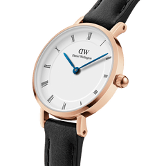 Close-up of the Petite Roman Numerals Sheffield Rose Gold watch, showing its white dial with Roman numerals, blue steel hands, rose gold case, and black leather strap.