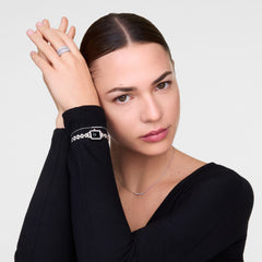 A woman wearing the Mirelle Eternity Bracelet Silver, showcasing its slim silver chain and curved bar set with white cubic zirconia crystals, styled with a black top for an elegant, minimalist look.