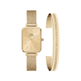 Rectangular gold mesh strap watch with a minimalist gold dial, paired with a matching polished gold cuff bracelet engraved with "Daniel Wellington", both featuring a refined and elegant design.