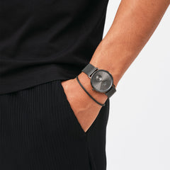 A person wears the Tide Mesh Bracelet Graphite 2.8 alongside a matching graphite mesh watch, showcasing a coordinated and minimalist style.