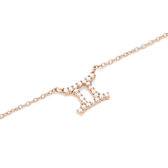 Close-up of a rose gold chain necklace featuring a Gemini zodiac pendant adorned with sparkling hand-set crystals.