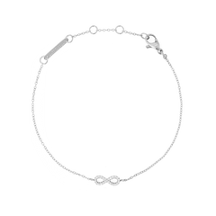 Delicate silver bracelet featuring a slender adjustable chain with a central infinity symbol adorned with white cubic zirconia crystals, crafted from polished stainless steel.