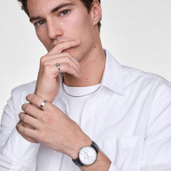 Man wearing the Classic Day Display Sheffield Silver watch with a black leather strap and white dial, styled with a white shirt and silver jewellery for a refined, modern look.