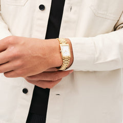 A person wearing the Bound 3-Link Gold watch with a rectangular gold case and three-link bracelet, styled with a cream shirt and black top.