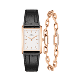 Rectangular rose gold watch with a white minimalist dial and black crocodile-embossed leather strap, paired with a rose gold chain bracelet featuring a crystal-encrusted link.