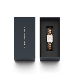 Quadro Lumine Bezel 5-Link Melrose women’s watch with a rectangular white dial and rose gold bracelet, elegantly presented in a dark gift box with Daniel Wellington branding.