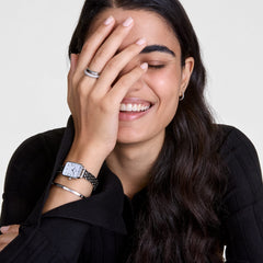 A woman wears the Classic Lumine Bracelet S, a slender silver cuff with sparkling crystals, styled alongside a silver Daniel Wellington watch for an elegant, layered look.