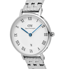 Close-up of the Daniel Wellington Petite Roman Numerals Date 5-link Silver watch, highlighting the polished stainless steel strap, white guilloché dial with black Roman numerals, blue hands, and date window at 6 o’clock.
