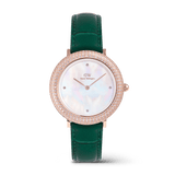 Rose gold women’s watch with a sparkling crystal-set bezel, mother of pearl dial, and an emerald green crocodile-textured leather strap.