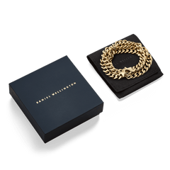 Ellipse Cuban Chain Necklace Gold presented coiled on a black pouch beside a navy Daniel Wellington gift box, showcasing its polished gold links and elegant packaging.