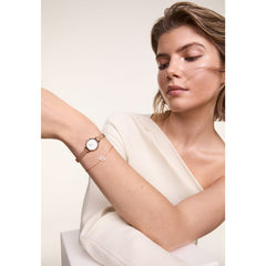 A woman wearing the Petite Mini Blush Melrose watch with a blush pink dial and rose gold mesh strap, styled alongside a delicate bracelet for an elegant, modern look.