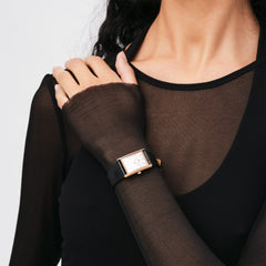 A woman wears the Bound Black Crocodile Rose Gold watch with a rectangular rose gold case and black crocodile-embossed leather strap, styled with a sheer black top.