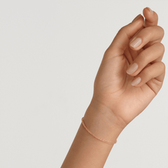 A slim rose gold twisted chain bracelet with a delicate rope design, shown worn on a wrist for a minimalist and elegant look.