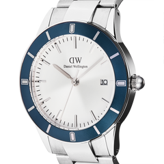 Close-up of the Daniel Wellington Iconic Paradigma Link Blue Bezel watch, highlighting the satin matte blue aluminium bezel, crisp white dial with date window, and polished stainless steel bracelet.