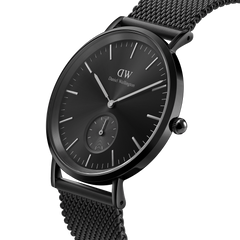 Classic Multi-Eye Ashfield Onyx watch with a black stainless steel mesh strap, minimalist black dial, and sub-dial for seconds, shown in a close-up angled view.