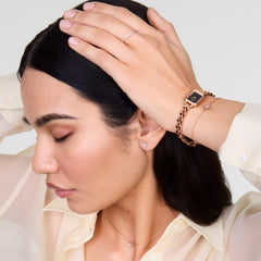 Woman wearing the Mirelle Star Necklace Rose Gold, styled with matching star-shaped earrings, a rose gold watch, and bracelet, showcasing the necklace’s delicate chain and sparkling star pendant against a light blouse.