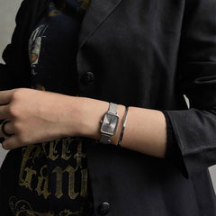 Quadro Pressed Unitone Silver ladies watch with mesh strap, styled on wrist with a silver bangle and black blazer.