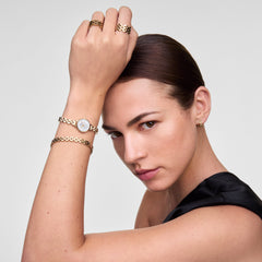 A woman wears the Petite Mini Arch 3-link White Gold watch on her wrist, styled with matching rose gold jewellery, highlighting the watch’s slim round case, white dial, and elegant arched bracelet for a refined, minimalist look.