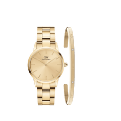 Gold Daniel Wellington watch with a minimalist dial and matching gold link strap, paired alongside a slender gold cuff bracelet featuring subtle crystal accents and engraved branding.