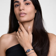 Woman wearing Quadro Mini Reflection Silver watch with rectangular mirror dial and polished mesh strap, styled with silver jewellery.