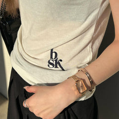Woman wearing the Quadro Pressed Unitone rose gold watch with a rectangular dial and mesh strap, styled alongside a matching rose gold bangle for a chic, modern look.
