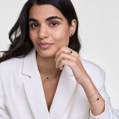 Woman wearing Audrey Ring Black Agathe Gold with matching black agate jewellery, styled with a white blazer for elegance.