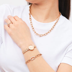 Woman wearing the Crystal Link Necklace Rose Gold, featuring chunky rose gold chain links and a central cubic zirconia-embellished link, styled with matching rose gold jewellery and a white top.