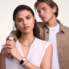 A woman wearing the Crystal Link Necklace Silver, featuring chunky silver links and a central crystal-embellished link, styled with a white sleeveless top and matching silver jewellery for a modern, elegant look.