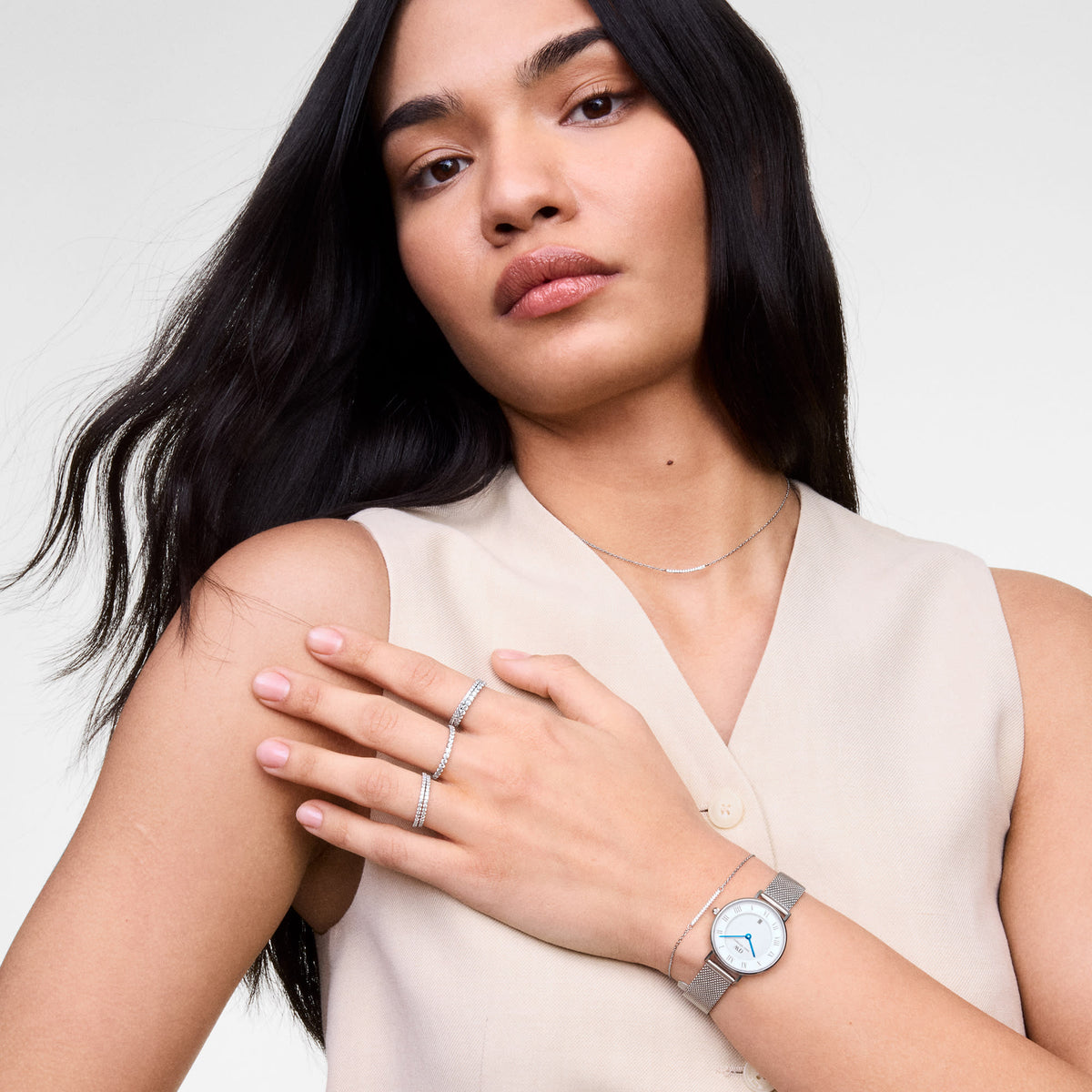Woman wearing the Mirelle Eternity Ring Silver 1.4 mm on her fingers, styled with a minimalist silver necklace and watch, showcasing the ring’s slender band and sparkling cubic zirconia crystals for an elegant, contemporary look.