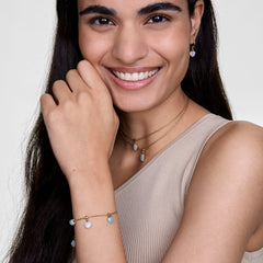 A woman wears the Amazonite Octagon Gold Charm on a delicate gold necklace, styled with matching gold jewellery including a bracelet and earrings, highlighting the charm’s soft blue-green stone and elegant, minimal design.
