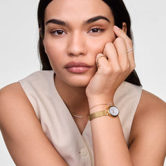 Woman wearing the Mirelle Eternity Bracelet Gold on her wrist, styled with a gold watch and minimalist rings, showcasing the bracelet’s delicate chain and sparkling cubic zirconia bar for an elegant everyday look.