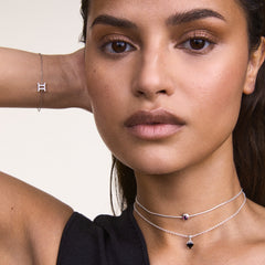 A woman wears the Charm Heart Crystal Black Silver on a delicate silver necklace, showcasing the heart-shaped black cubic zirconia pendant styled with layered chains for an elegant, modern look.