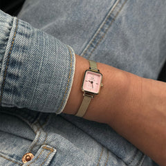 Quadro Mini Evergold Blush women’s watch with a rectangular gold case, blush pink dial, and gold mesh strap, styled on a wrist with casual denim clothing.
