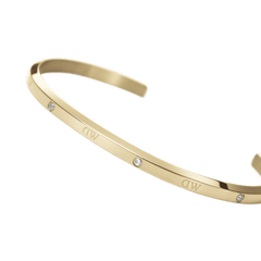 Elegant Classic Lumine Bracelet G in polished gold, featuring a slim open cuff design with six sparkling crystals and subtle DW engraving along the band.