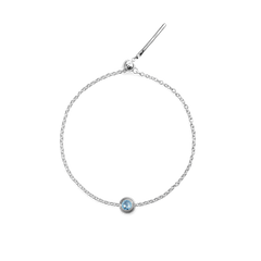 Delicate sterling silver bracelet featuring a fine chain and a central round blue crystal charm in a minimalist setting.