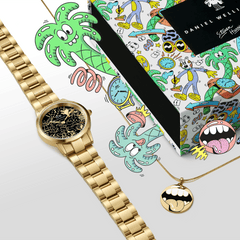 Steven Harrington x DW SET featuring a gold Daniel Wellington watch with a black illustrated dial and a matching gold pendant necklace, presented alongside a vibrant, artist-designed gift box decorated with playful cartoon graphics.