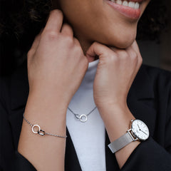 Woman wearing Petite Sterling silver mesh watch with minimalist white dial, styled with matching silver jewellery and black blazer.