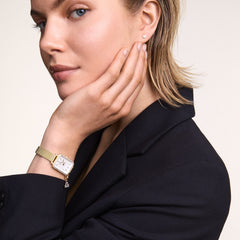 Woman wearing the Quadro Crystal Zodiac Evergold Set, featuring a gold mesh strap, rectangular crystal bezel, white mother of pearl dial, and a sparkling zodiac charm, styled with a black blazer for an elegant, modern look.