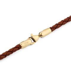 Detail view of the Daniel Braided Leather Bracelet St Mawes 2.8 Gold, highlighting the polished gold-tone lobster clasp engraved with DW and the finely braided brown leather band.