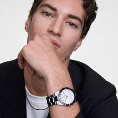 A man wearing the Iconic Paradigma Link Black Bezel watch, featuring a silver dial, black aluminium bezel, and polished stainless steel bracelet, styled with a black blazer and white top for a smart, modern look.